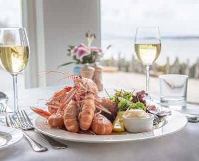 Plate of langoustines and glasses of white wine served at Crinan Hotel.