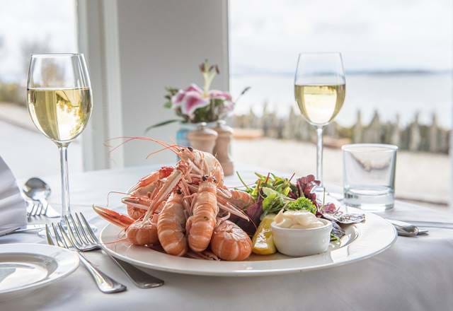 Plate of langoustines and glasses of white wine served at Crinan Hotel.