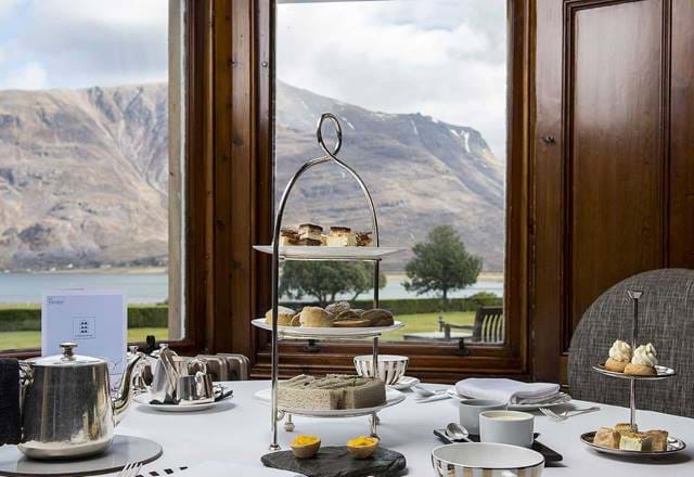 Afternoon tea set at The Torridon by a large window with a mountain and loch view in the background.