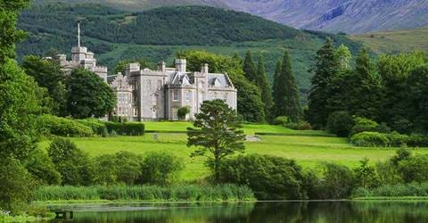 The grand castle of Inverlochy in Scotland surrounded by lush green landscapes with mountains in the background.